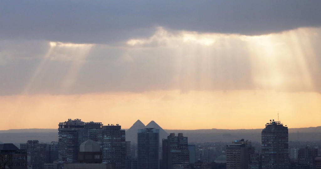 Rays of the sun appear behind clouds over the Great Pyramids (C) of Giza during a cold weather around country and the capital city of Cairo