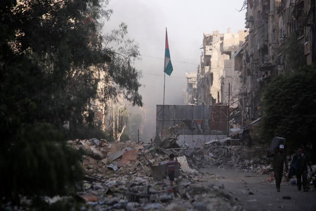 A boy stands on the rubble of damage buildings in Yarmouk Palestinian camp in Damascus 