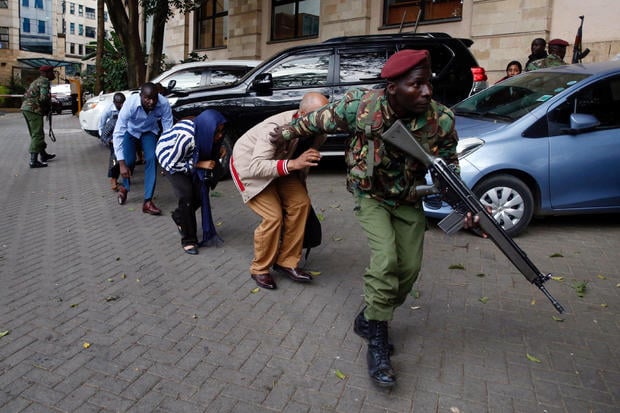 People are evacuated by a member of security forces at the scene where explosions and gunshots were heard at the Dusit hotel compound, in Nairobi 