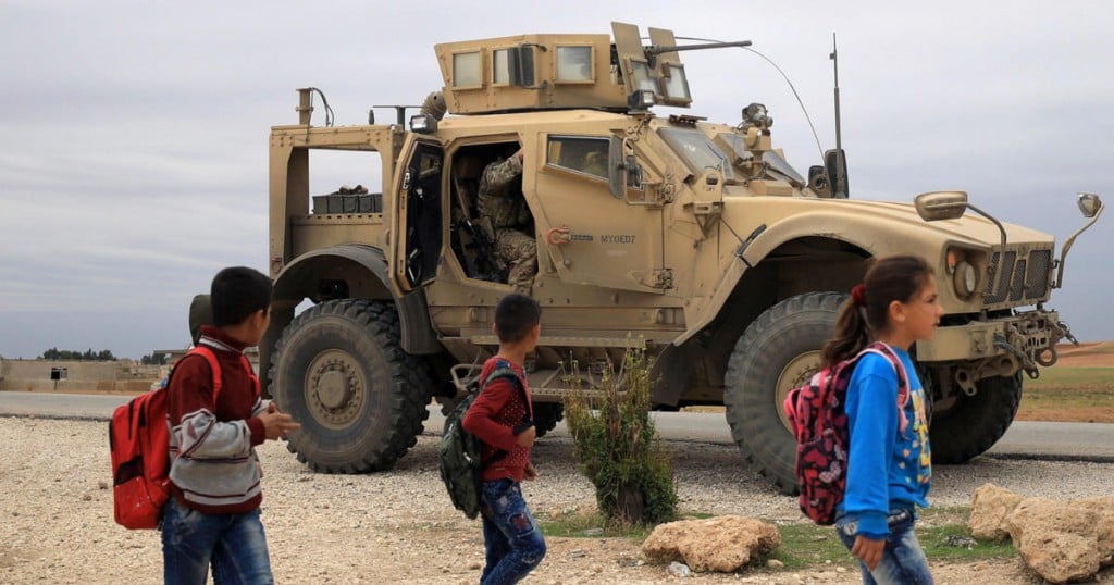 FILE PHOTO: Syrian schoolchildren walk as U.S. troops patrol near Turkish border in Hasakah