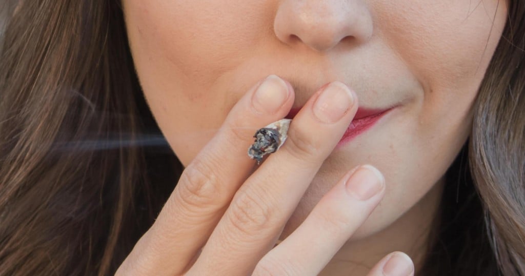Up-close to a pretty young woman smoking a joint