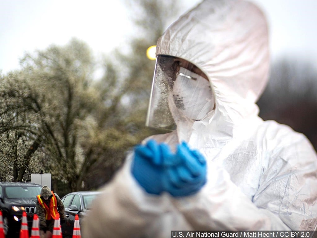 A nurse changes out gloves while New Jersey National Guard Airmen direct traffic at a COVID-19 Community-Based Testing site.