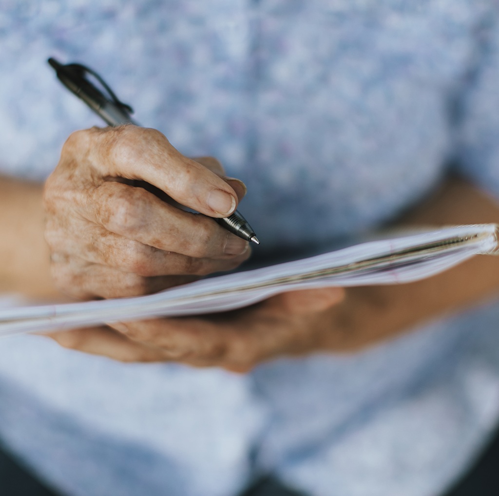 Senior Woman Writing Down Her Memories Into A Notebook