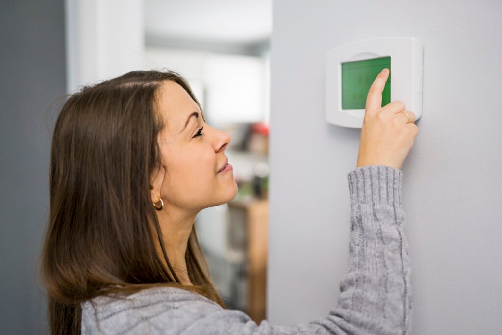 Woman Set The Thermostat At House.