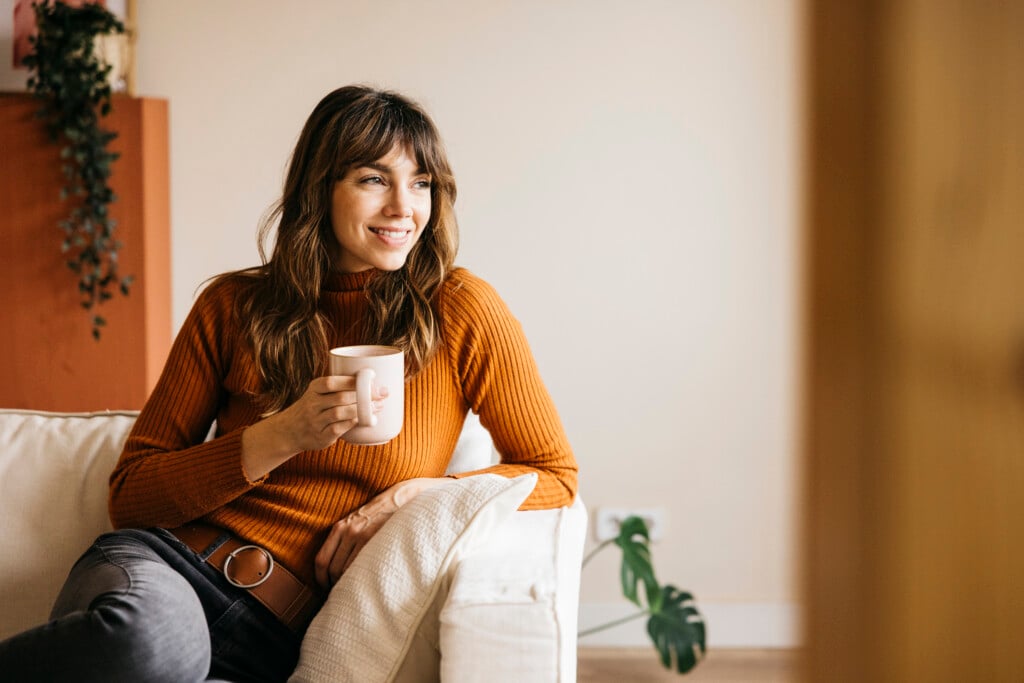 Young Adult Woman Relaxing On Sofa Drinking Coffee