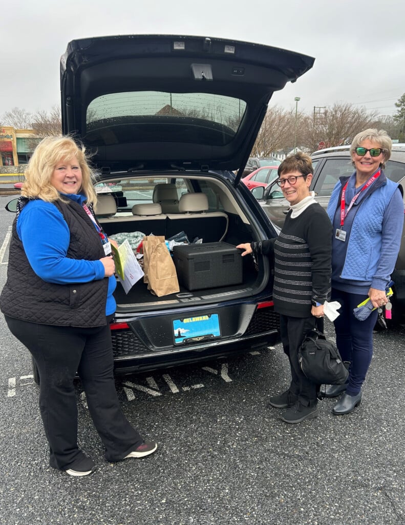 CHEER Volunteers Valerie Zarro (Left), Sussex County Councilwoman Jane Gruenebaum and Jeanie Blomquist (Far Right) pack food in containers into the trunk of a car to deliver to seniors in Sussex County. (CHEER)