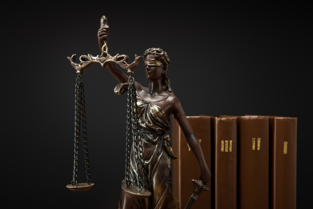 Bronze Statuette With Scales Of Justice And Volumes Of Brown Books Isolated On Black