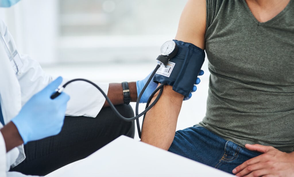 Shot Of A Doctor Examining A Man With A Blood Pressure Gauge.