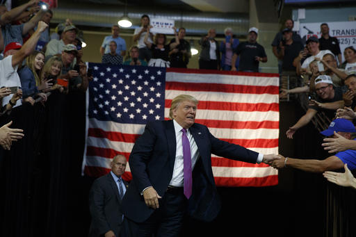 Republican presidential candidate Donald Trump shakes hands as he arrives to a campaign rally at Xfinity Arena of Everett
