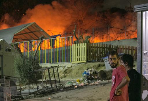 Migrants watch a large fire as it burns inside the Moria refugee camp on the northeastern Greek island of Lesbos