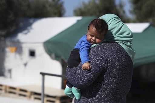A woman carries her baby at the Kara Tepe camp for refugees and other migrants in Lesbos island
