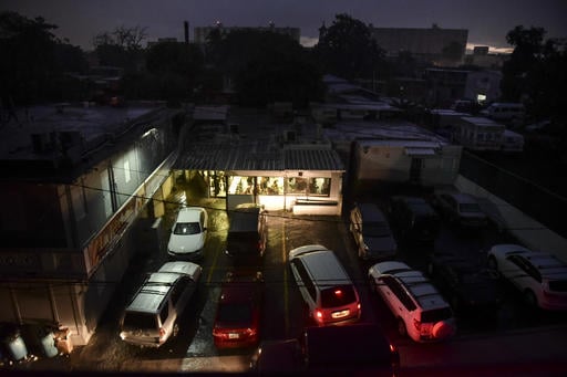 Motorists illuminate a storefront with their headlights as they drive in to buy bread after a massive blackout