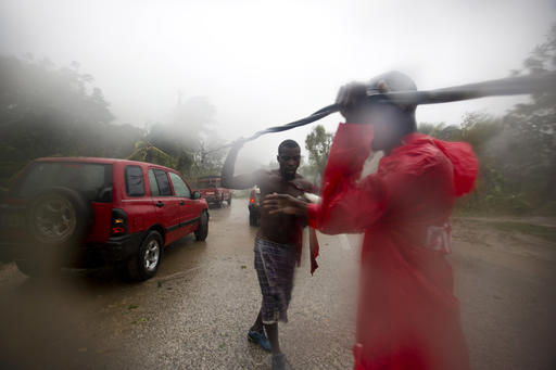 Two men remove a downed power line to allow vehicles passage