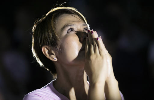 A Thai woman puts her hands together in prayer at Siriraj Hospital where Thai King Bhumibol Adulyadej was being treated in Bangkok