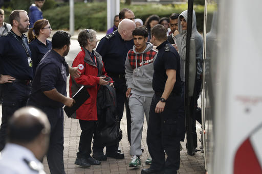 Two unidentified young migrants get off a bus as they arrive at Lunar House