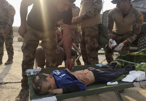 Soldiers give the first aid to a boy injured during the clashes between Iraq's elite counterterrorism forces and Islamic State militia in the village of Tob Zawa