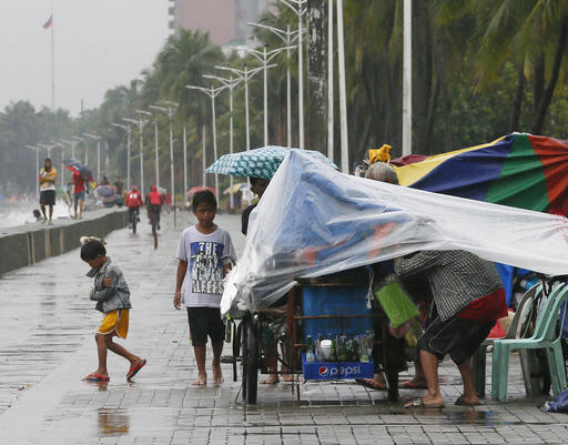 A few residents walk on a promenade under a slight rain brought about by Typhoon "Karika" Sunday