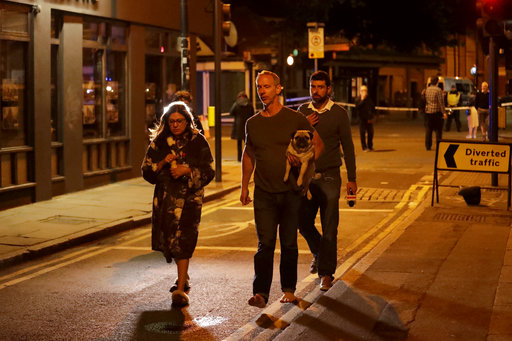 A man carries a dog with a woman wearing a dressing gown after an attack in London