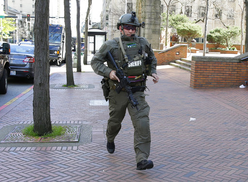 A King County Sheriff's Deputy carries a gun as he runs near the scene of a shooting involving several police officers in downtown Seattle
