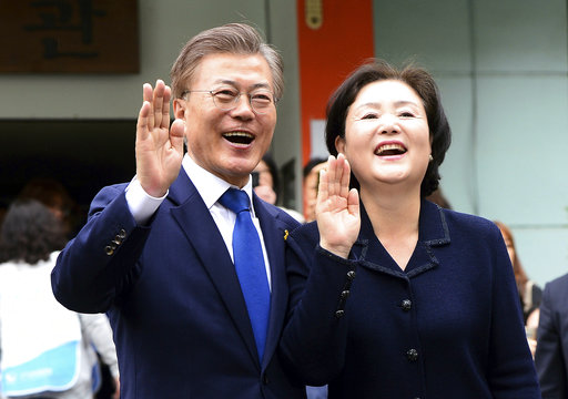 South Korean presidential candidate Moon Jae-in of the Democratic Party and his wife Kim Jung-suk wave after voting for a presidential election at a junior high school in Seoul