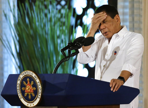 Philippine President Rodrigo Duterte touches his head during his speech at the swearing in of officials of various municipalities at the Malacanang presidential palace in Manila