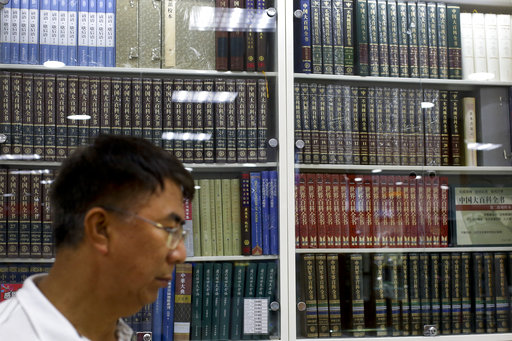 A Chinese man walks by a cabinets displaying Chinese encyclopedias at a book store in Beijing