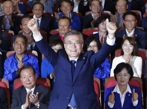 South Korea's presidential candidate Moon Jae-in of the Democratic Party raises his hands as his party leaders and members watch on television local media's results of exit polls for the presidential election in Seoul