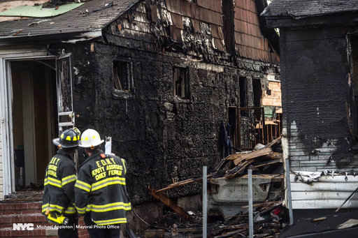 New York Fire Department personnel stand outside the scene of a deadly fire Sunday