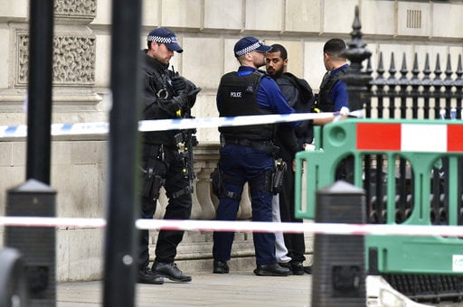 Armed police talk to man at the scene after a person was arrested following an incident in Whitehall in London