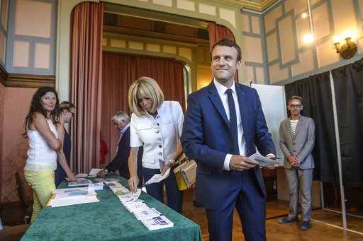 French President Emmanuel Macron and his wife Brigitte Macron pick up ballots before voting in the first round of the two-stage legislative elections in Le Touquet