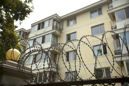Coils of barbed wire top a fence next to an apartment building where Liu Xia