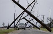 A driver works his way through a maze of fallen utility poles damaged in the wake of Hurricane Harvey