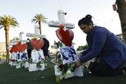 Cece Navarrette places flowers at a cross for her cousin