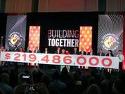 Relatives of A. James Clark and board members of the A. James and Alice B. Clark Foundation hold a scroll with the $219.5 million written across that the foundation is donating to the University of Maryland for scholarships and capital projects during the announcement in College Park