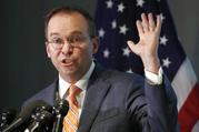 Mick Mulvaney holds up his hand as he speaks during a news conference after his first day as acting director of the Consumer Financial Protection Bureau in Washington