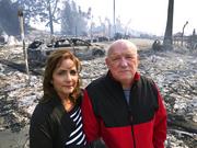 Linda and John Keasler pose for a photo in front of the ruins of their home at the Hawaiian Village Apartments