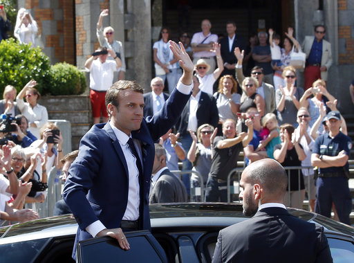 French President Emmanuel Macron waves to the audience as he leaves a polling station in Le Touquet