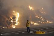 A firefighter covers his eyes as he walks past a burning hillside in Santa Rosa