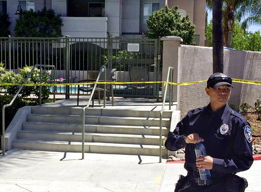 A police officer stands outside the pool area at an apartment complex Monday