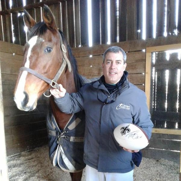 Dr. Christopher Johnson with Misszoey Belle after he saved the mare's life in surgery and was given an autographed football by New Orleans Saints quarterback Drew Brees at Old Friends Farm in Georgetown