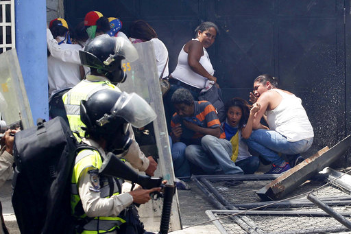 Anti-government demonstrators take cover from advancing Bolivarian Police officers during protests in Caracas