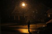 A person walks under a street light as snow falls