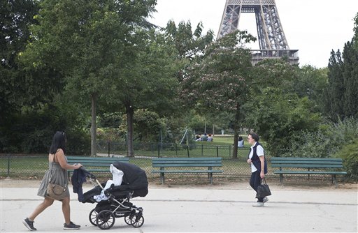 People stroll in the Champ de Mars garden near the Eiffel Tower