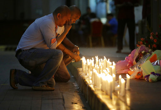 A man holds back tears as he lights candles for victims in an attack at the Resorts World Manila complex