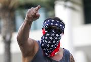 A demonstrator masked with a U.S. flag protests outside of California Republican Convention in Anaheim