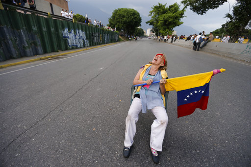 A woman sits on a highway ramp as anti-government protesters stage sit-ins to disrupt traffic throughout Caracas