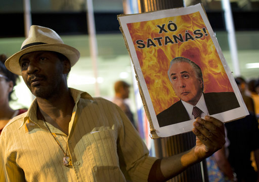 A demonstrator holds a photo of Brazil's President Michel Temer that reads in Spanish "Get out Satan!" in Rio de Janeiro