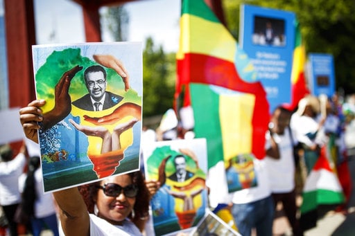 A woman holds a portrait of Tedros Adhanom Ghebreyesus from Ethiopia