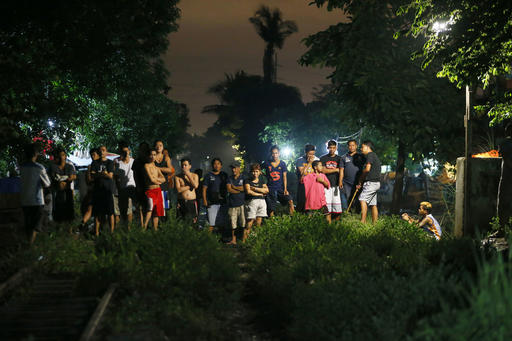 Residents are kept at a distance as police investigators examine the bodies of three suspects who were killed in an alleged "buy-bust" operation by the authorities in the continuing "War on Drugs" campaign of Philippine President Rodrigo Duterte before dawn Friday
