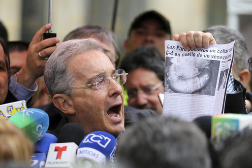 Former President and opposition Senator Alvaro Uribe shows a clip of a news article with a headline reading in Spanish "FARC puts a C4 collar around the neck of a Venezuelan